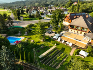 Luftaufnahme des Hotel Restaurant Zollner mit umliegender Gartenanlage, Parkplätzen und Blick auf die Natur in Kärnten.